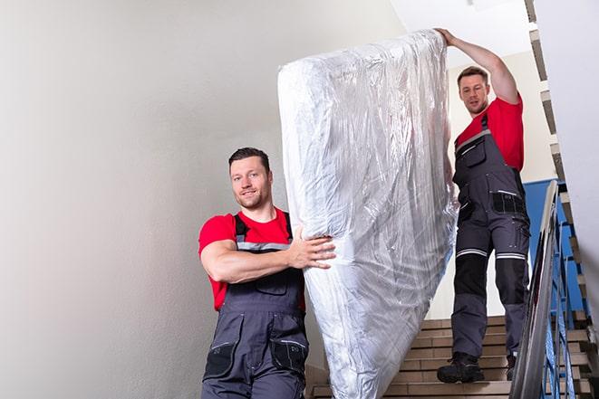 heavy lifting workers transporting a box spring out of a building in Mendota Heights, MN